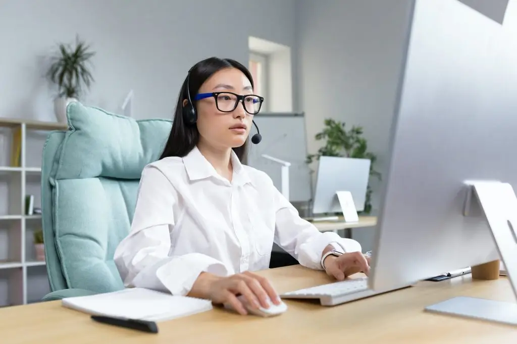 Am I Too Old to Learn Mandarin? 2 Online distance learning. Asian teacher in headphones sitting at a table teaching a lesson online
