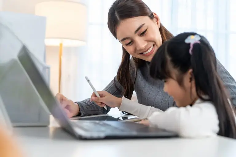 Asian little young girl kid learning online class at home with mother.