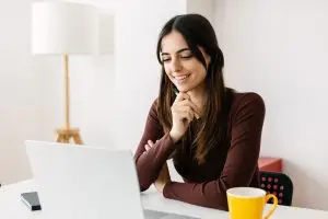Home 8 Portrait of young adult student sitting on table using laptop learning online
