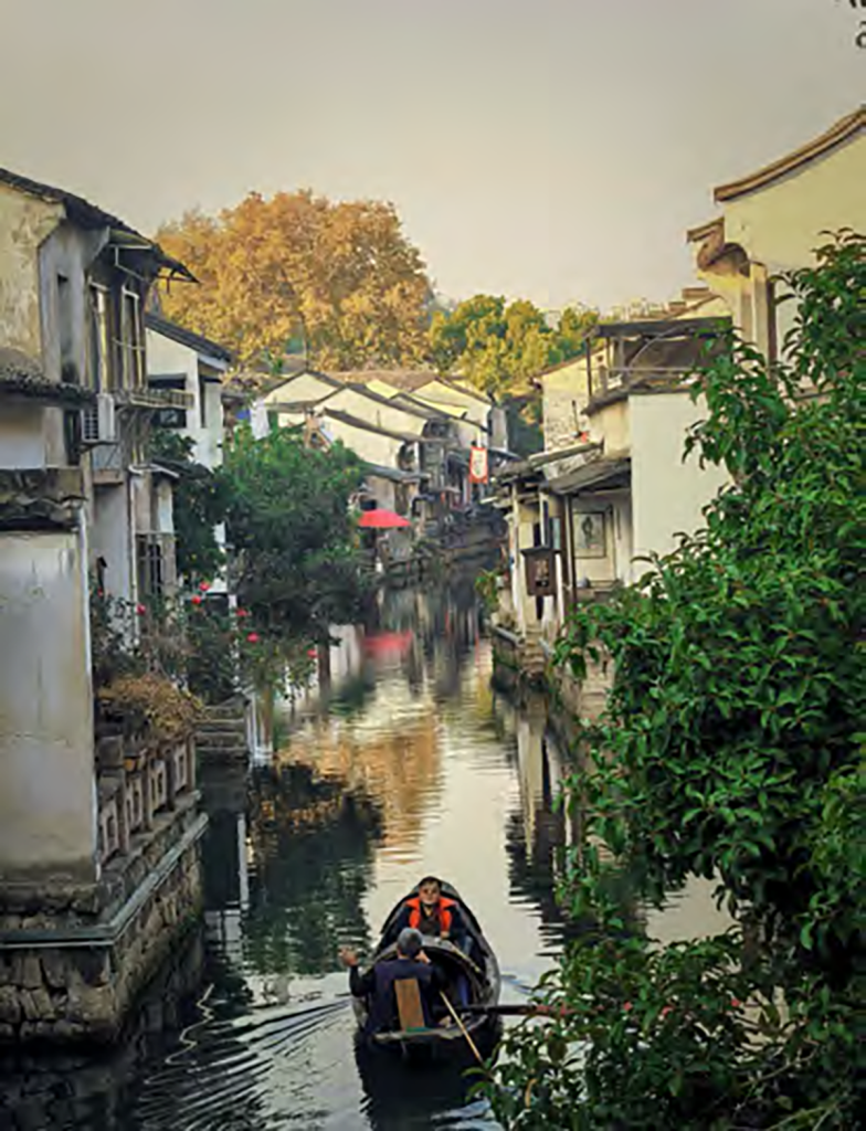 Boat on a canal lined with white-walled houses in a Jiangnan water town near Shaoxing, China